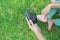 Close up mother hands putting small shoes to her son in the green lawn