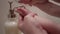 Close up on mother helping baby wash her hands with soap in sink