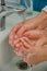 Close up mother helping little girl to wash her hands to prevent virus and germs. Covid