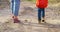 Close-up of mother's and child's feet walking in the woods on a sunny fall day