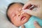 Close up mother use cotton bud to clean baby eyes