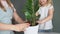 Close up mother wearing apron and daughter transplant plant. Happy family put soil in white pot. Home gardening