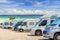 Close up motorhomes parked in a row on white sand beach and blue sky background