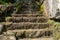 Close up of mountain stream flowing down stone steps in summertime. Manmade decorative waterfall flows down old stairs