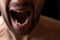 Close-up mouth of angry man screaming. Threat of violence.