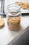 Close-up muesli in glass jar on parchment paper on baking sheet, above. Made homemade granola, healthy breakfast