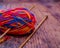 Close up of a multi coloured ball of knitting yarn and bamboo knitting needles on a wooden floor