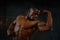 Close-up muscles of african american handsome body builder posing with naked torso on the black studio background