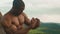 Close-up of muscular african american athletic man with naked torso showing his muscles. Green mountain nature