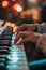 Close-up of musician's hands playing on a synthesizer keyboard with glowing buttons and studio background.