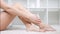 Close-up naked legs with perfect skin applying moisturizing cream by hands side view
