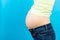 Close up of naked pregnant woman`s belly wearing opened jeans at colorful background with copy space. Pregnancy concept