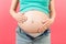 Close up of naked pregnant woman`s belly wearing opened jeans at colorful background with copy space. Pregnancy concept