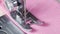 Close up of needle moving and sewing on sewing machine. Sewing pink material