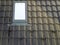 Close-up of new attic plastic window installed in shingled house roof. Professionally done building and construction work, roofing