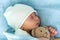 Close-up of Newborn Baby Face Portrait Early Days Sleeping With Tady Bear On Blue Background. Child At Start Minutes Of