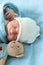 Close-up of Newborn Baby Face Portrait Early Days Sleeping With Tady Bear On Blue Background. Child At Start Minutes Of