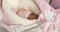 Close-up of a newborn baby in a pink hat and overalls.