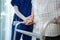 Close up of nurse help disable man walk with walker at nursing home. Caregiver therapist doctor support senior older handicapped