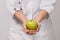 Close-up nutritionist is a young woman holding an apple in her hand. The concept of losing weight in the patient