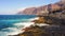 Close-up ocean foamy waves rolling at rocky shore. Aerial view of transparent turquoise picturesque water hitting