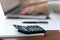 Close up office calculator on table, female hands typing on laptop