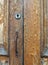 Close up of an old brown varnished peeling wooden door with keyhole and rusty handle