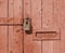 Close up of an old brown wooden door with faded paint and a rusty closed padlock and old metal letterbox