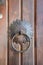 Close-up of old brown wooden massive gate, closed door, handmade iron handles and knockers