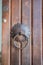 Close-up of old brown wooden massive gate, closed door, handmade iron handles and knockers