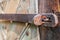 Close-up of an old, corroded and rusty padlock closing the wooden door. Details of wood and metal structure and soft focus
