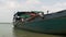 close up of an old dredging boat tied up at riverbank, pipe sections kept outside the water