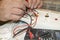 Close-up of the old electrician`s hand, the use of digital voltmeter for voltage to repair the electric iron, selective