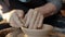 Close-up of old master`s hands making beautiful bowl on spinning wheel in workshop