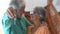 Close up of old and mature woman and man at home holding keys of house to the camera. Portrait of couple of senior smiling and loo