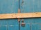 close up of an old peeling green painted wooden plank door barred shut with a piece of timber and rusty nails with a lock and