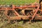 Close up of a old red and rusty cultivator used for cultivating agricultural land