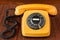 Close up of an old, scratched orange rotary dial telephone