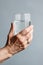 Close-up of an old woman holding a glass of water with hand. The concept of loneliness