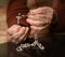 Close up of old woman praying with silver rosary with cross