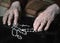 Close up of old woman praying with silver rosary with cross