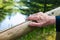 Close-up of old womans hand resting at a railing in nature