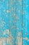 Close up of a old wooden door, teal blue paint peeling off; text