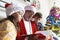 Close-up of older man dressed as Santa Claus reading a story to two children at home