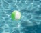 Close-up one bright green beach ball in swimming pool sunny day