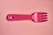 Close-up of one childish plastic pink forks on a pale pink background. Dishes for a picnic