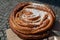 Close up of one large traditional Swedish Cinnamon Bun or Kanelbullar, with small sugar crystals, displayed for sale at a street f