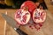 Close up of one whole and two half pomegranates fruits and a damascus kitchen knife on a wooden cutting board