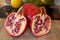 Close up of one whole and two half pomegranates fruits on a wooden cutting board