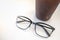 Close up oof readding glasses with plastic cup of iced black coffee on white table